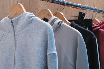 Poster - A rack of clothes with a gray hoodie and a black and red hoodie. The gray hoodie is the most visible