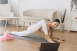 © anatoliycherkas - Young woman practicing yoga at home following online class on laptop