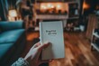 © AHNH3 - Hand Holding a Drug-Free Journey Notebook in Cozy Living Room