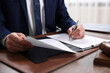 © New Africa - Notary signing document at table in office, closeup