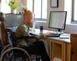 © Wavebreak Media - Man in wheelchair working on laptop at office desk, analyzing data spreadsheets