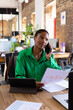 © Wavebreak Media - Businesswoman in green shirt discussing charts on phone at modern office desk