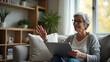 © HaJung - Mature Woman in 60s Engages in Family Video Call from Home Couch