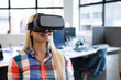 © WavebreakMediaMicro - Smiling woman using VR headset in modern office, exploring virtual reality