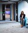 © Wavebreak Media - Businesswoman holding tablet sitting in modern office hallway, looking focused, copy space