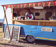 © Wavebreak Media - Smiling vendor serving drinks from colorful food truck at outdoor market