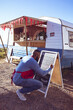 © Wavebreak Media - Man writing menu on chalkboard outside food truck, preparing for customers