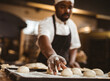 © Wavebreak Media - Baker in kitchen preparing dough balls on floured baking tray, focused on work