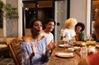 © Wavebreak Media - Diverse friends enjoying dinner party, laughing and sharing stories at patio table