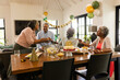 © Wavebreak Media - Diverse senior friends celebrating 60th birthday with cake and decorations at home, sharing joy