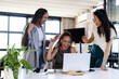 © Wavebreak Media - Celebrating success, diverse businesswomen using laptop together in modern office