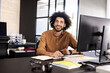© Wavebreak Media - Smiling man working at desk with computer and notepad in modern office