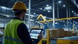 © Jam - A worker monitors automated sorting systems using a tablet in a high-tech warehouse equipped with robotic machinery
