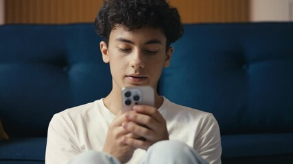 Sad teen boy reading a bad news text on his phone, struggling with cyberbullying
