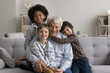 © fizkes - Grandparent greatest treasure. Warm family portrait senior grandfather celebrate birthday sit on comfy couch in tight hugs of loving small grandkids multiethnic cousins look at camera with happy smile