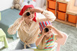© Pixel-Shot - Nanny with little girl in bandanas looking through spyglasses at home