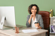 © Pixel-Shot - Mature happy businesswoman holding cup of coffee at workplace with modern computer in office