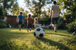 © lashkhidzetim - group of children playing soccer in a grassy field. The soccer ball is in the foreground, and the children are running around it