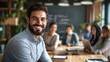 © Karo - Young businessman smiling and looking at the camera while sitting in front of a group or team during a conference.