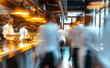 © Curioso.Photography - A blurred motion shot of chefs working in a busy professional kitchen with warm overhead lighting, creating a dynamic and active cooking environment.