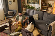 © pressmaster - Family enjoying quality time together in cozy living room with carpeted floor and modern furniture, playing with plush toys and using electronic device, having fun and bonding