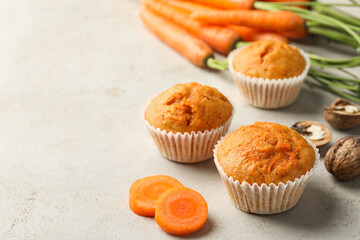 Wall Mural - tasty carrot muffins, fresh vegetables and walnuts on light grey table, closeup. space for text