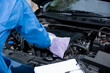 © sorapop - Close up of Hand Mechanic Asian man writing on a paper with wearing blue shirt. Professional mechanic repairing a car in auto repair shop.
