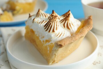 Wall Mural - piece of delicious pie with browned meringue on light blue table, closeup