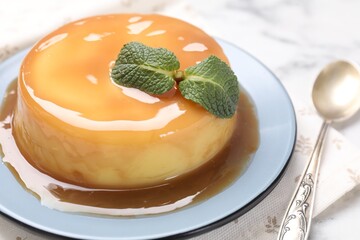 Wall Mural - delicious pudding with caramel sauce and mint on white table, closeup