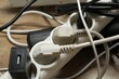 © New Africa - Extension power boards overloaded with plugs on wooden floor, closeup
