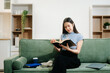 © Nuttapong punna - Young asian woman relax on comfortable couch at home texting messaging on smartphone and tablet
