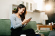 © Nuttapong punna - Asian woman using the smartphone and tablet on the sofa at home.