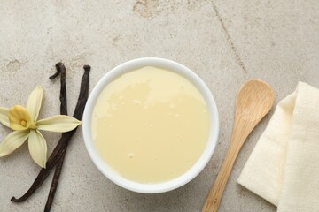 Wall Mural - tasty condensed milk, vanilla pods, flower and spoon on light grey table, flat lay