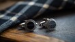 © Entri - Stylish black onyx cufflinks on wooden surface with checkered fabric