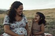 © Valerii - Joyful moments shared between a pregnant mother and her young daughter in a serene landscape during golden hour