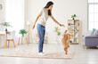 © Studio Romantic - Young happy smiling female owner playing with joyful little cute dog at home with a toy enjoying leisure together. Cheerful woman training her pet in living room. Animal care and love concept.
