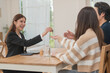 © surachetkhamsuk - Estate agent hands house keys to the client. Asian woman realtor gives keys to the couple buyer while sitting at a table with a house model. Real estate