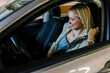 © Mediteraneo - Pretty blonde woman putting her seatbelt on in car.