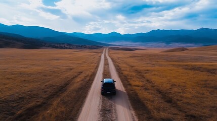 Aufkleber - Aerial view of a car driving on a dirt road through golden fields against a breathtaking mountain backdrop : Generative AI