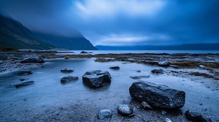 Aufkleber - Mysterious rocky shoreline under moody clouds reflecting on still water at twilight : Generative AI