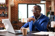 © DC Studio - African american male analyst seated at desk with pen in hand, analyzing online financial documents on his laptop in startup office. Focused black man using digital device to research strategy ideas.