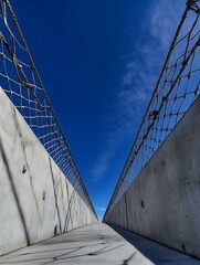 Aufkleber - Modern architecture featuring an empty pedestrian walkway with a striking view of blue skies framed by concrete walls : Generative AI