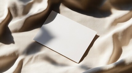 blank card on draped beige silk fabric with shadows