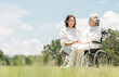 © buritora - 公園にいる車椅子に乗ったシニア女性と介助する女性（介護・親子・老人ホーム）