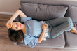 © Kolomiiets Viktoriia - A beautiful woman with long brown hair is lying on the couch at home. Top view