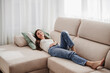 © Westend61 - Woman relaxing on a sofa at home smiling