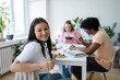 © Westend61 - Asian woman smiling at camera while having lunch with friends indoors