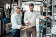 © Westend61 - Male engineers discussing over equipment while standing in factory