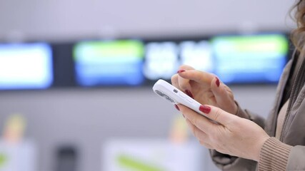 Woman is holding a cell phone in her hand. She is looking at the screen and she is focused on something. Concept of modern technology and the importance of staying connected in today's world