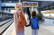 © zhukovvvlad - Mom and child with backpacks are waiting for the train on the platform. The family is ready to travel. We are going on vacation with small children.